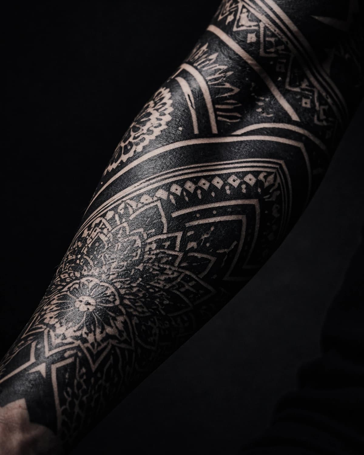 Blackwork forearm piece with flowing ornamental negative space